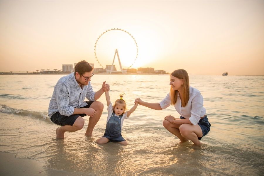 A family on Dubai beach with Ain Dubai in the background