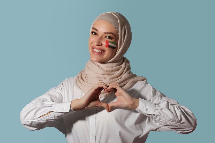 Happy woman in hijab with UAE national flag painted on cheek