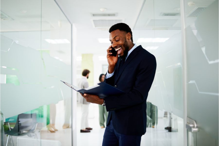 Smiling businessman reading documents and having phone call