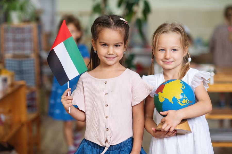 Two girls holding a globe and a flag of the UAE
