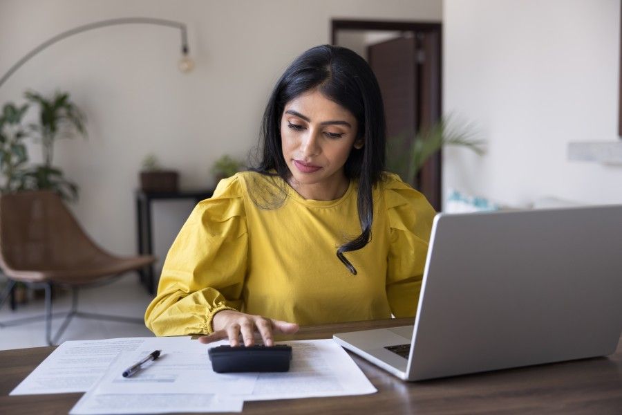Woman reading documents while working on a laptop